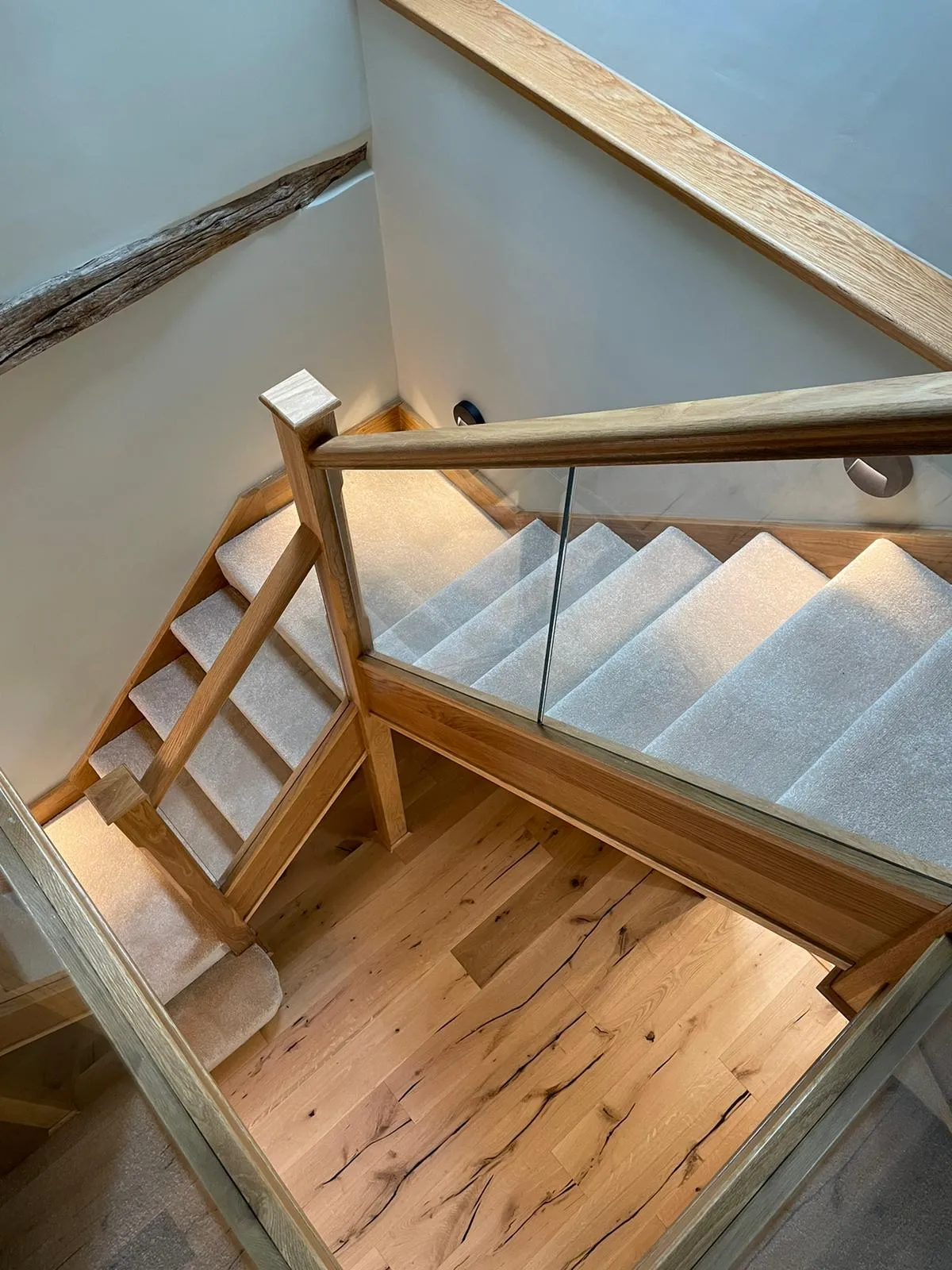 a staircase with a wooden handrail and carpeted steps
