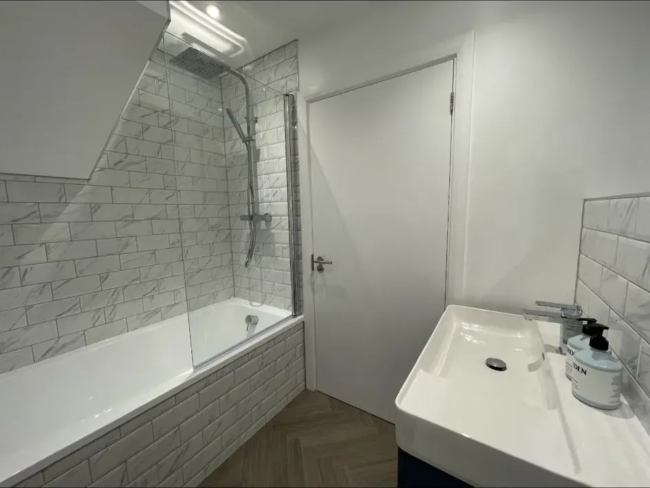 A bathroom with a sink, mirror and bathtub.