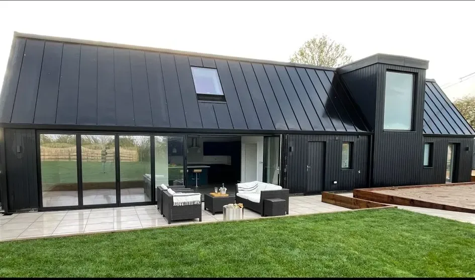 A black house with a deck and patio.